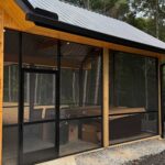 Screened patio with black frame and wide openings for unobstructed views of the surrounding woods.